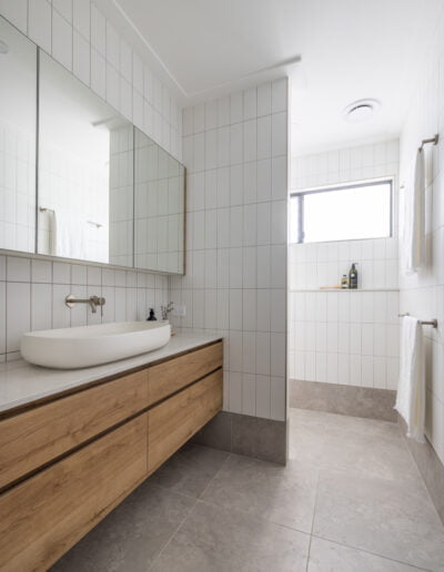 Contemporary bathroom with grey marbled floors, white subway walls, timber vanity and mirror cabinet.